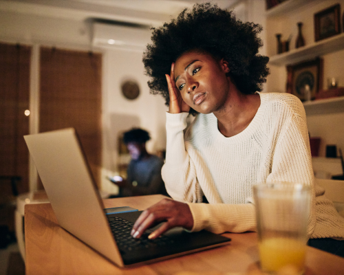 woman sitting infront of laptop at night time looking tired